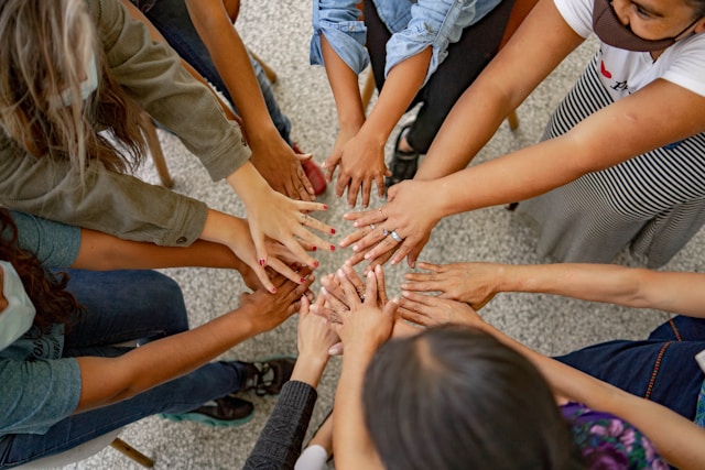 A circle of community members joining hands together in a show of solidarity and mutual support
