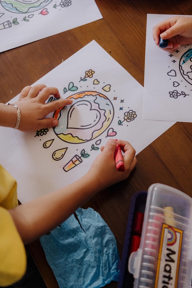 Children's hands coloring heart-shaped drawings with crayons — a small act of love and care that reflects Agape's mission